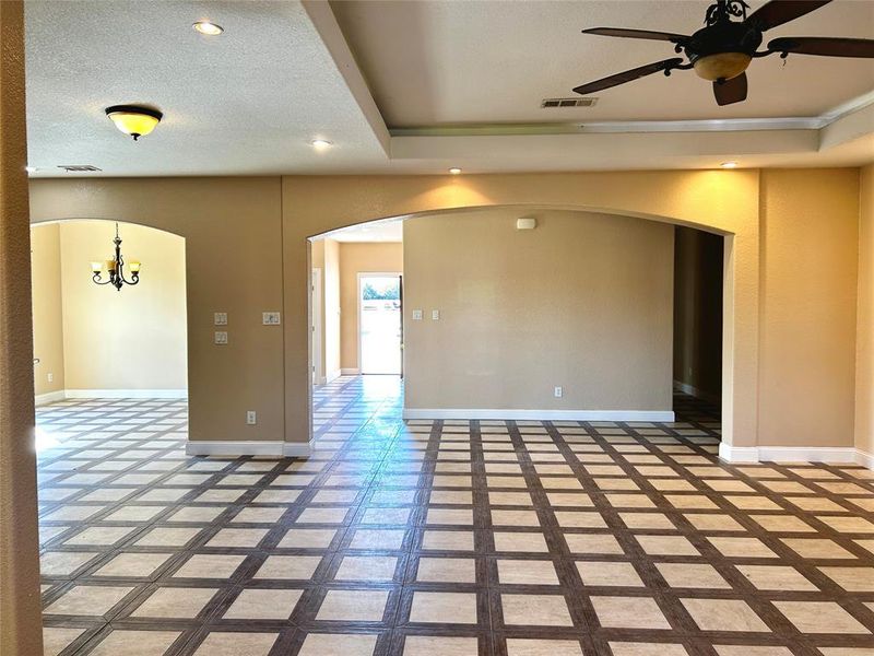 Unfurnished room with ceiling fan with notable chandelier, a textured ceiling, and a tray ceiling