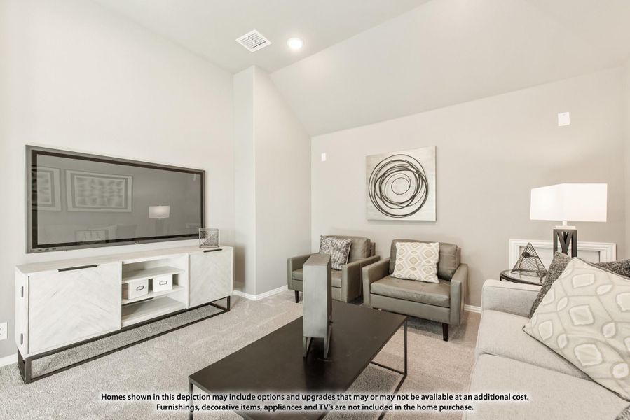 Living room with vaulted ceiling, large wall-mounted TV, gray seating, and carpeted floors Living room with vaulted ceiling, large wall-mounted TV, gray seating, and carpeted floors
