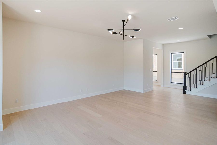 Spare room featuring a chandelier, recessed lighting, light wood-type flooring, and stairway