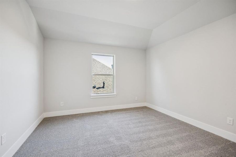 Empty room featuring light colored carpet and lofted ceiling