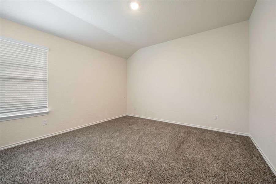 Carpeted spare room with lofted ceiling and baseboards