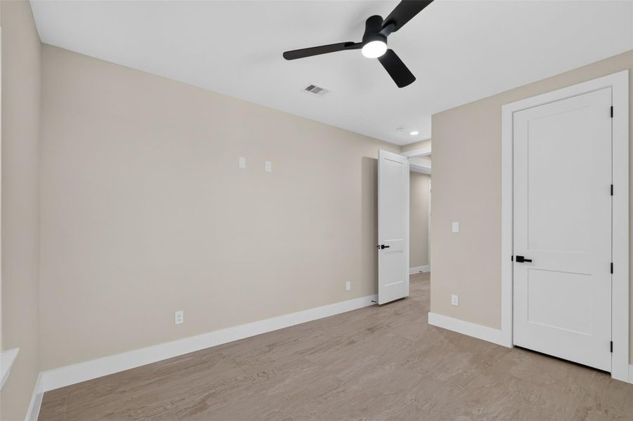 Bright and modern room with sleek wood flooring, neutral walls, and a stylish ceiling fan, offering a contemporary and inviting space.