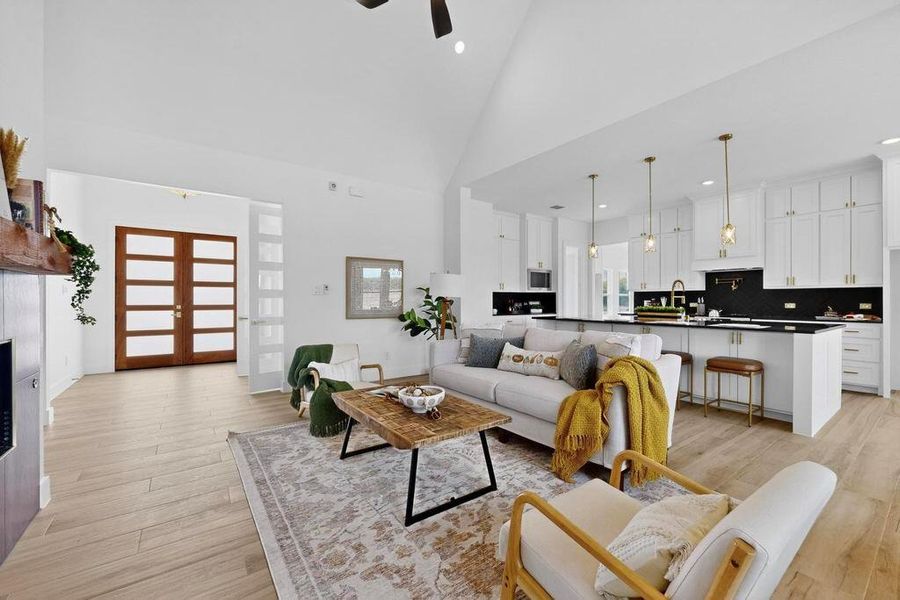Living area featuring high vaulted ceiling, french doors, light wood-style flooring, recessed lighting, and healthy amount of natural light