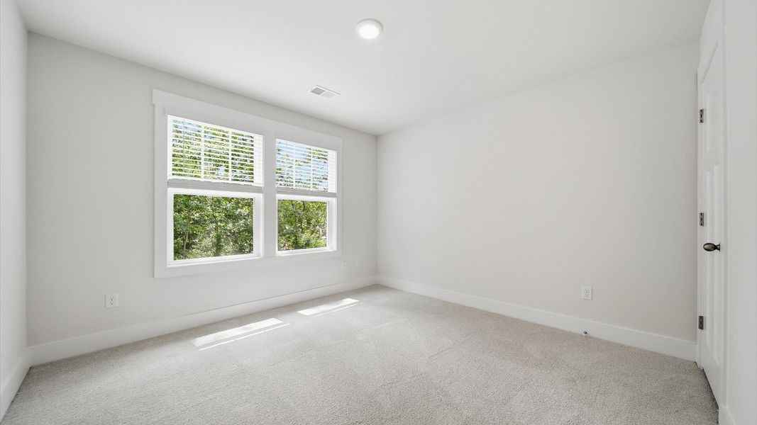 Elegant bedroom retreat featuring soft carpet and oversized windows that create a bright, welcoming space Elegant bedroom retreat featuring soft carpet and oversized windows that create a bright, welcoming space