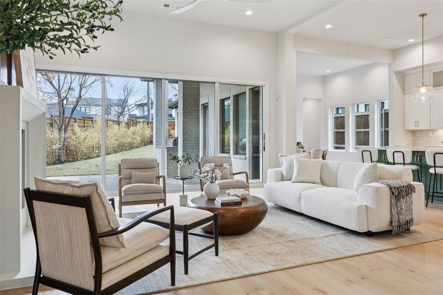 Living area with light wood-style floors, recessed lighting, and a high ceiling