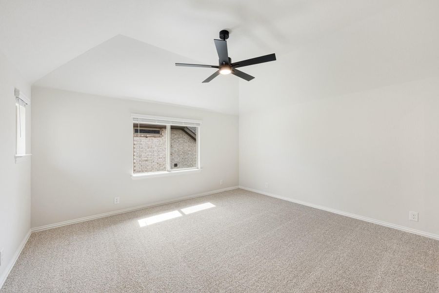 Empty bedroom with vaulted ceiling, black ceiling fan, carpet flooring, and a single window Empty bedroom with vaulted ceiling, black ceiling fan, carpet flooring, and a single window