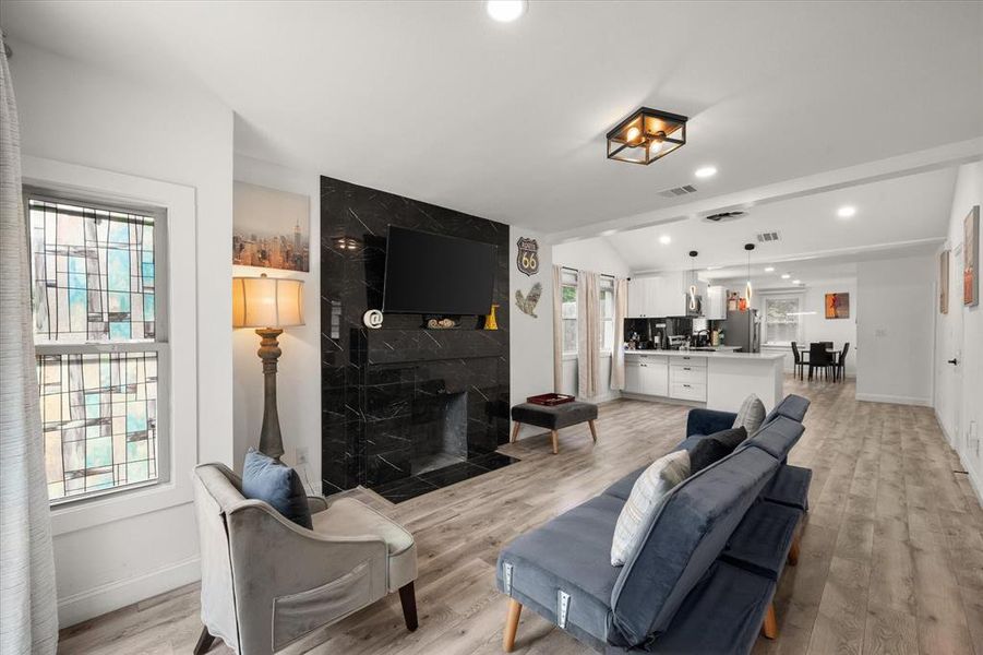 Living room with plenty of natural light, a fireplace, light wood-type flooring, lofted ceiling, and recessed lighting Living room with plenty of natural light, a fireplace, light wood-type flooring, lofted ceiling, and recessed lighting