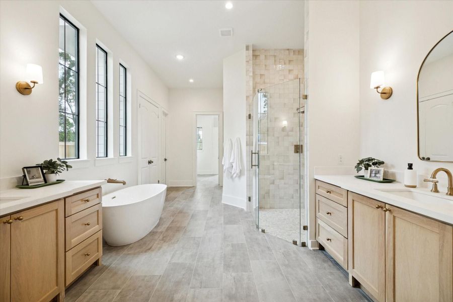 Luxurious primary bath with double vanities, soaking tub, walk-in shower, and elegant tile finishes.