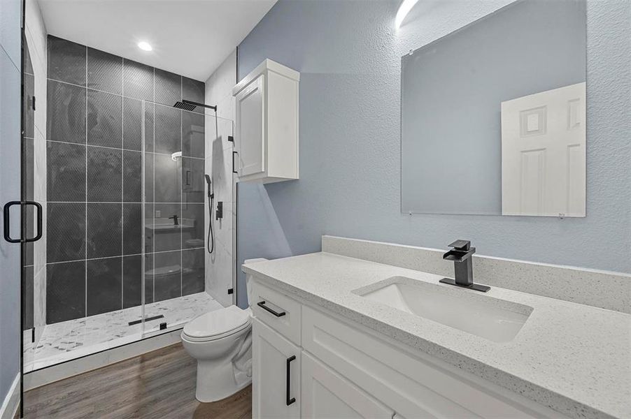 Bathroom featuring vanity, toilet, hardwood / wood-style flooring, and an enclosed shower