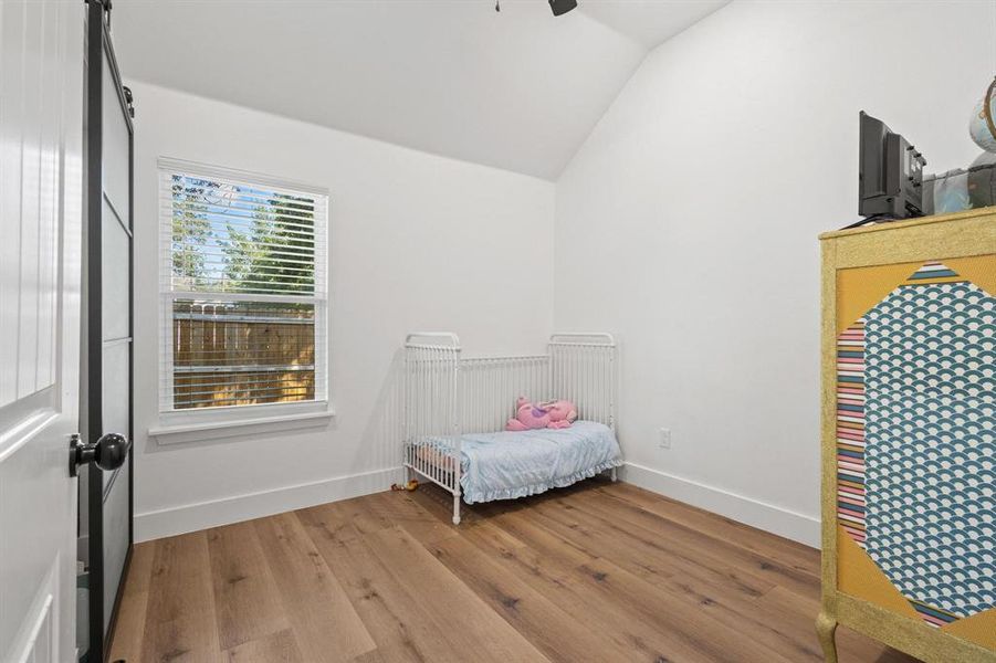 Bedroom featuring light wood-style flooring, vaulted ceiling, and a ceiling fan