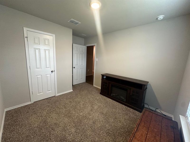 Unfurnished bedroom featuring dark carpet and a glass covered fireplace