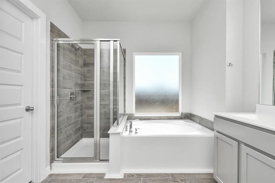 The primary en-suite has a soaking tub to give you that spa experience. The large privacy window allow lots of nature light in the space. Sample photo of completed home with similar floor plan. As-built interior colors and selections may vary.