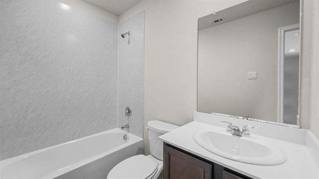 Bathroom featuring a single vanity with a white countertop, an integrated sink, a dark wood-finish cabinet, and an overhead mirror