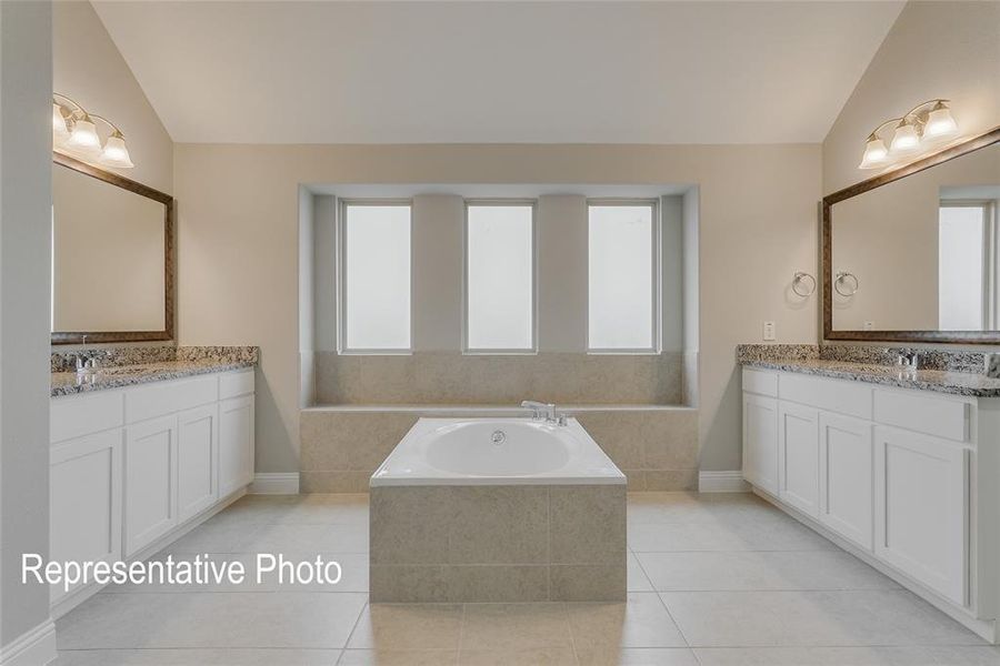 Bathroom featuring double vanity, tile patterned flooring, and a relaxing tiled tub