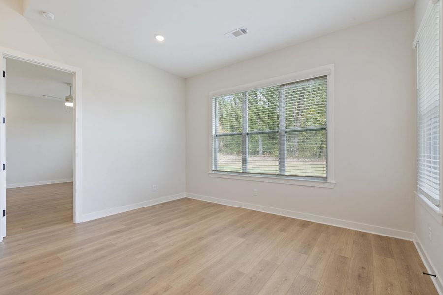 Recessed lighting, wood-finish flooring, and a large window with blinds