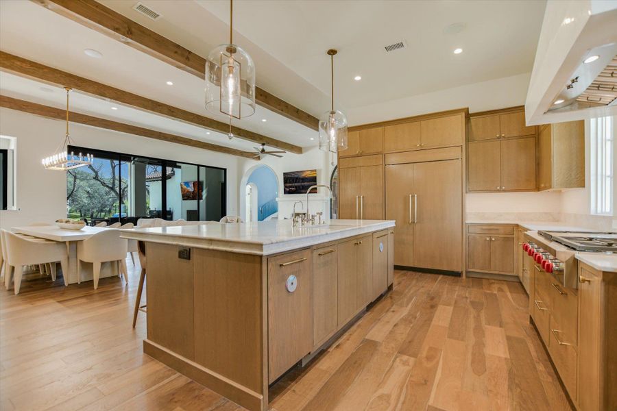 Kitchen with pendant lighting, extractor fan, light wood-type flooring, a spacious island, and beam ceiling