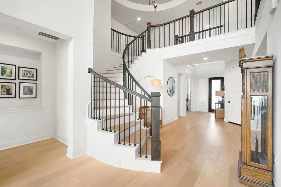 Grand entry hall featuring a sweeping curved staircase with dark wood newel posts and iron balusters Grand entry hall featuring a sweeping curved staircase with dark wood newel posts and iron balusters