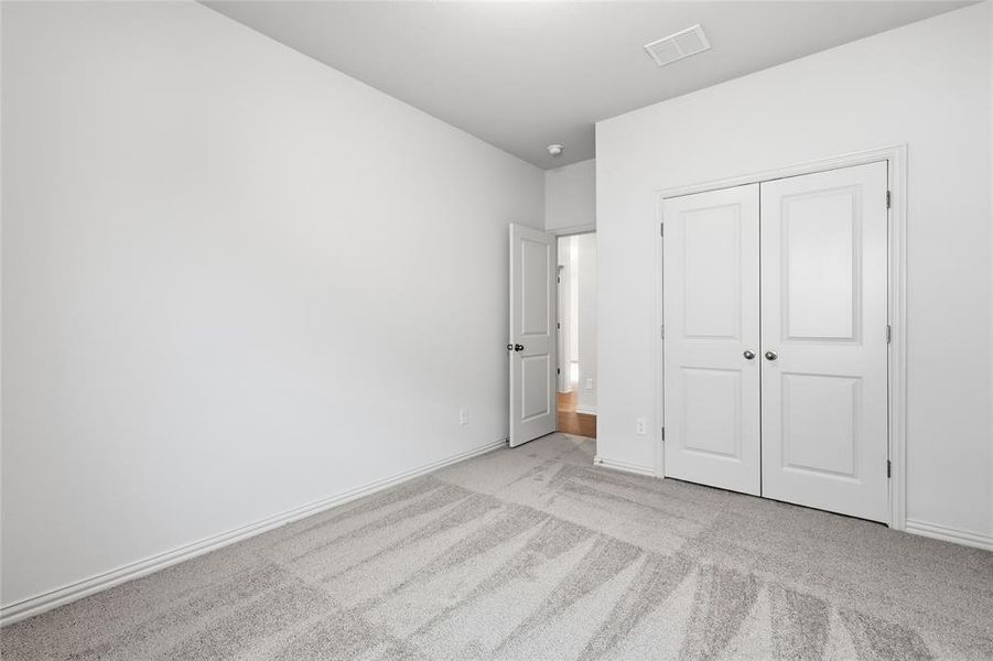 Unfurnished bedroom featuring light colored carpet and a closet