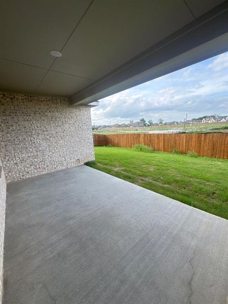 Expansive covered patio featuring a concrete surface, brick wall, and integrated ceiling light