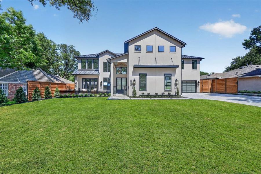 Contemporary stucco exterior with a dark-pitched roof, abundant front lawn, and a two-car garage with a frosted glass door Contemporary stucco exterior with a dark-pitched roof, abundant front lawn, and a two-car garage with a frosted glass door