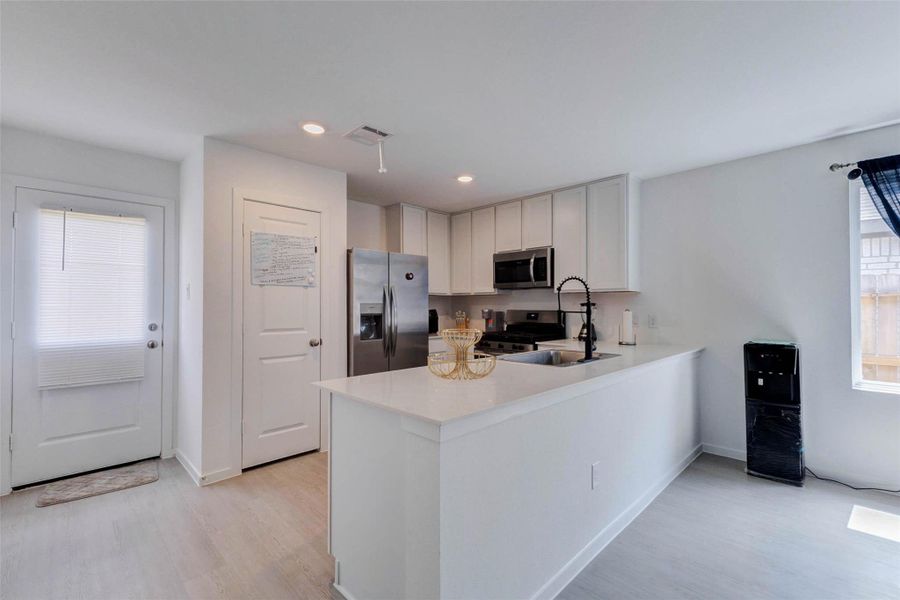 Modern kitchen featuring quartz countertops, stainless steel appliances, ample cabinet space, and a breakfast bar.