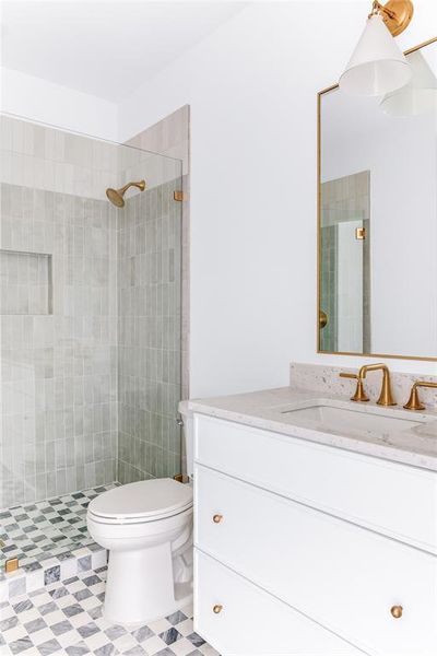 Bathroom featuring vanity, toilet, and tiled shower