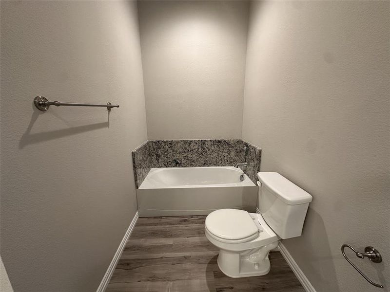 Bathroom with hardwood / wood-style floors, toilet, and a bathing tub