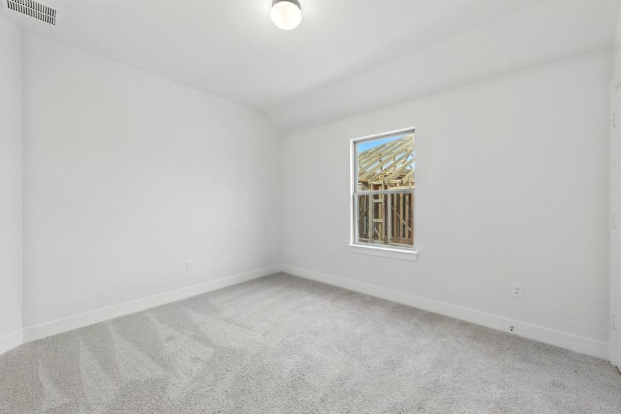 Carpeted empty room with baseboards and lofted ceiling Carpeted empty room with baseboards and lofted ceiling