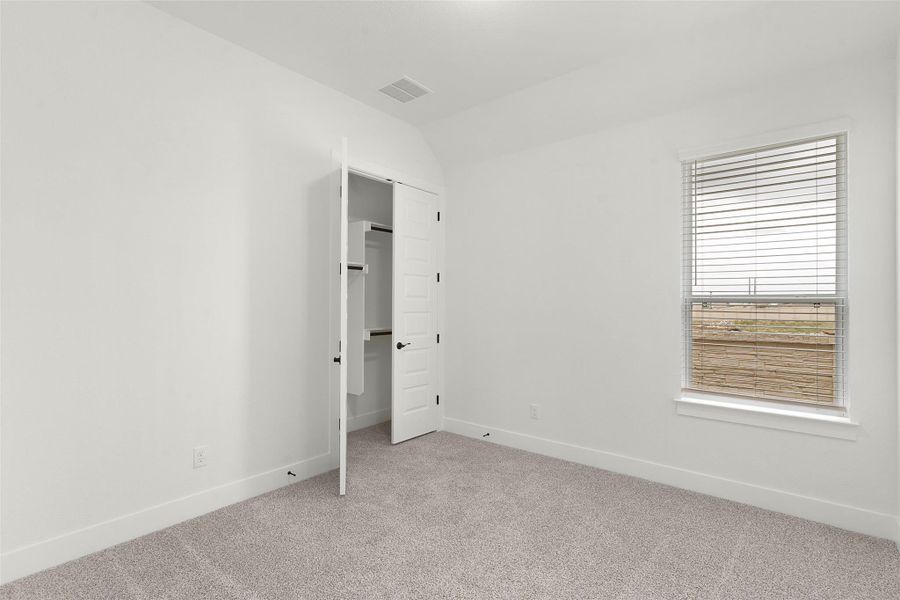 Unfurnished bedroom with light carpet and vaulted ceiling Unfurnished bedroom with light carpet and vaulted ceiling