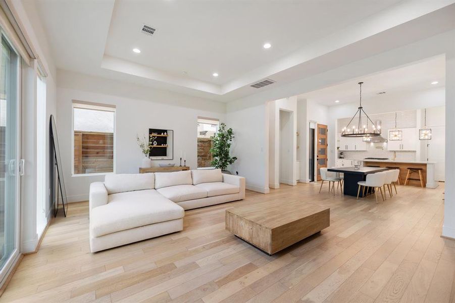 The expansive open-concept living area showcases elegant engineered wood floors and oversized windows that flood the space with natural light, offering a perfect setting for both cozy gatherings and grand entertaining.