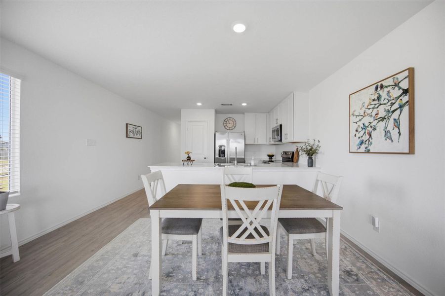 Gleaming luxury vinyl floors anchor this airy, open-concept dining area adjacent to the kitchen.