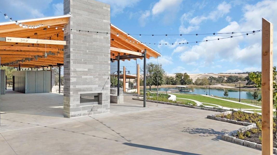 View of patio with a glass covered fireplace, a water view, and a pergola