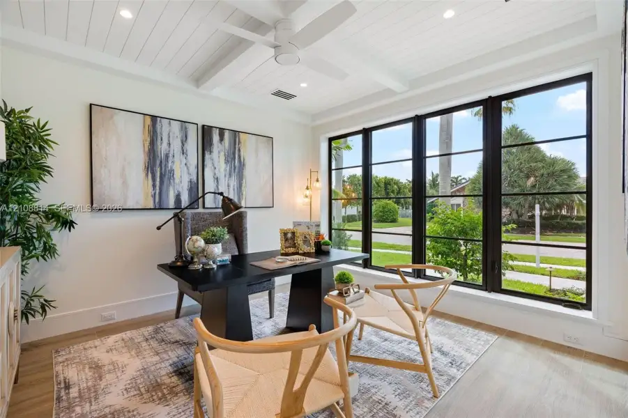 Beamed ceiling with white tongue-and-groove paneling, expansive multi-pane window wall with black frames, porcelain-finish flooring, and integrated recessed lighting Beamed ceiling with white tongue-and-groove paneling, expansive multi-pane window wall with black frames, porcelain-finish flooring, and integrated recessed lighting