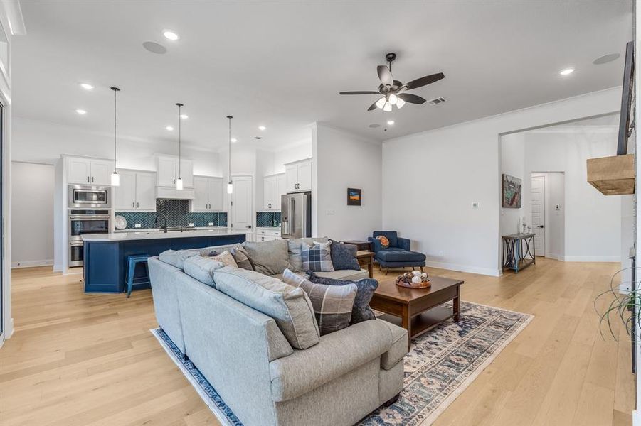 Living room featuring light hardwood / wood-style floors, ceiling fan, and crown molding