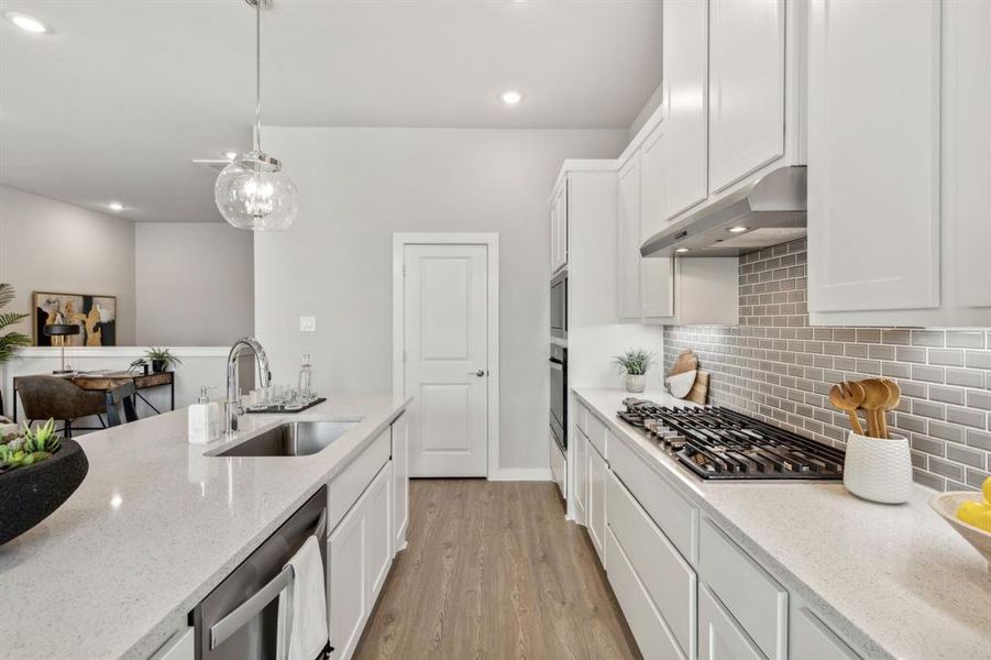 Kitchen featuring appliances with stainless steel finishes, sink, light stone counters, light hardwood / wood-style floors, and decorative backsplash