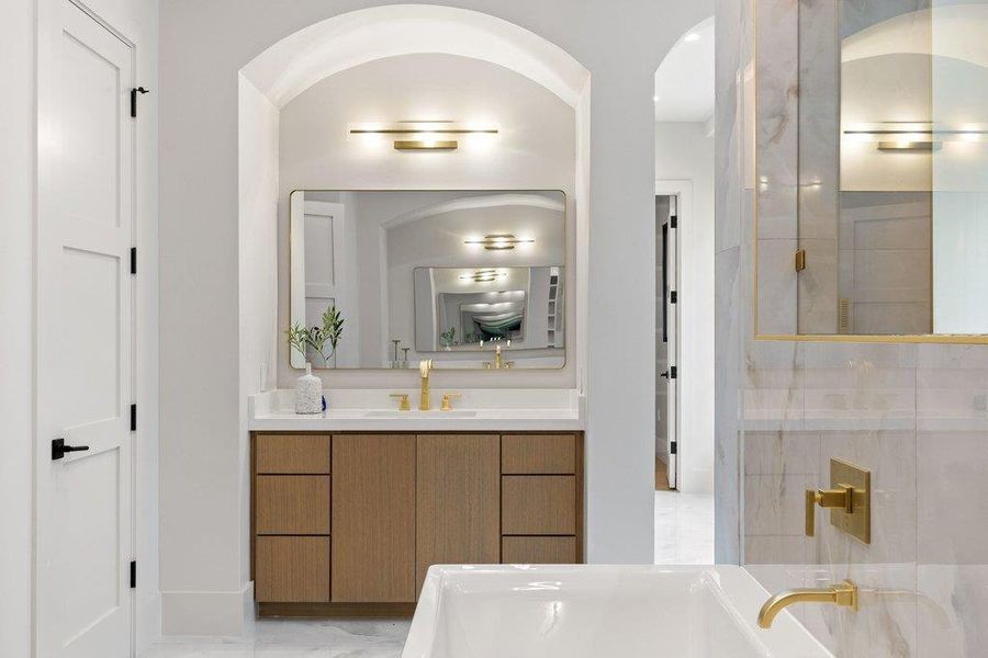 Custom vanity with light wood-finish cabinetry, white countertop, and gold-toned fixtures