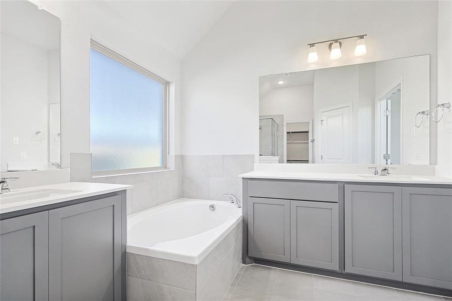 Bathroom with tile patterned flooring, vanity, vaulted ceiling, and separate shower and tub