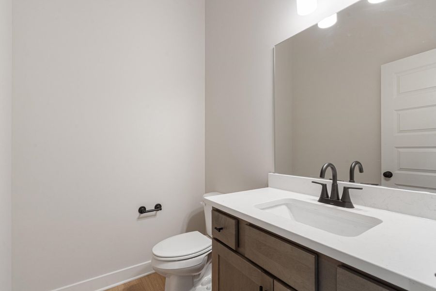 Bathroom featuring a wood-finish vanity with a white countertop, under-mount sink, and matte black faucet Bathroom featuring a wood-finish vanity with a white countertop, under-mount sink, and matte black faucet