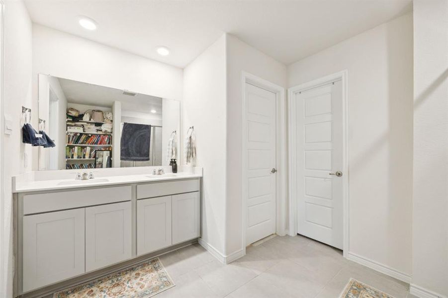 Full bath featuring double vanity, a walk in closet, and light tile patterned floors