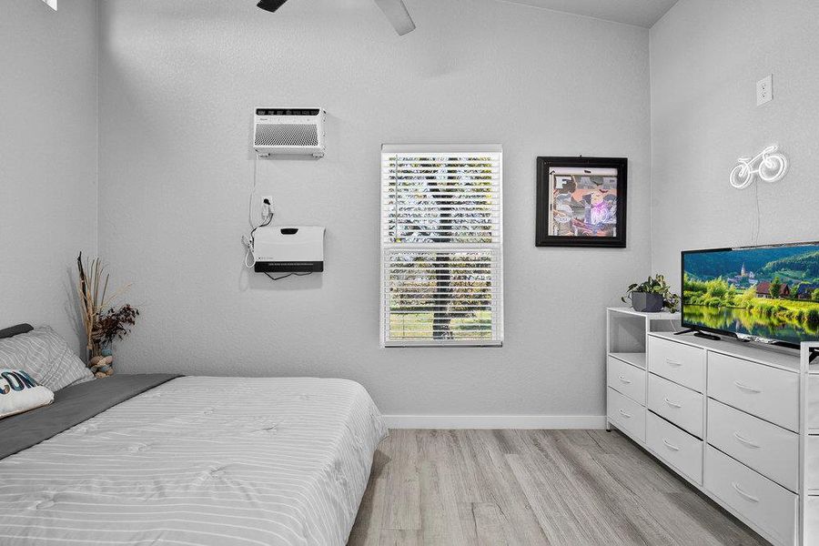 Bedroom with light wood-type flooring, ceiling fan, and lofted ceiling.