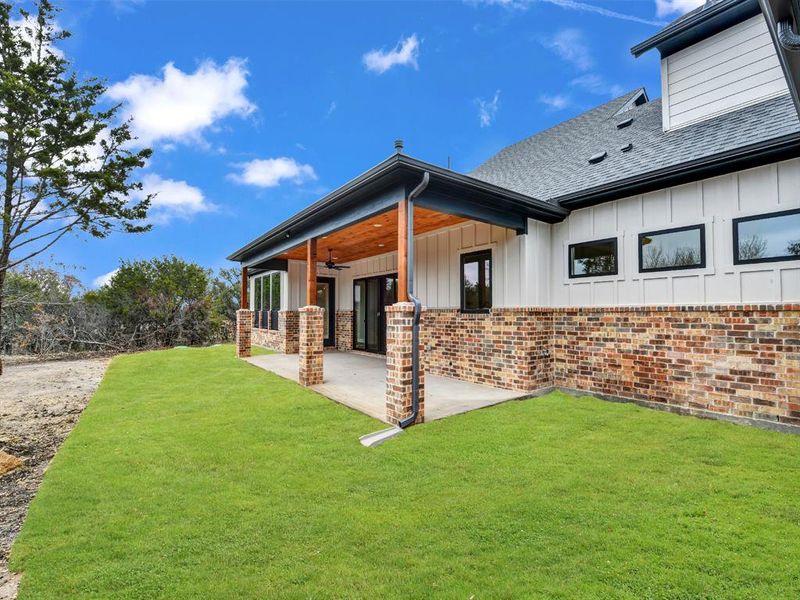 Rear view of house featuring a lawn, ceiling fan, and a patio