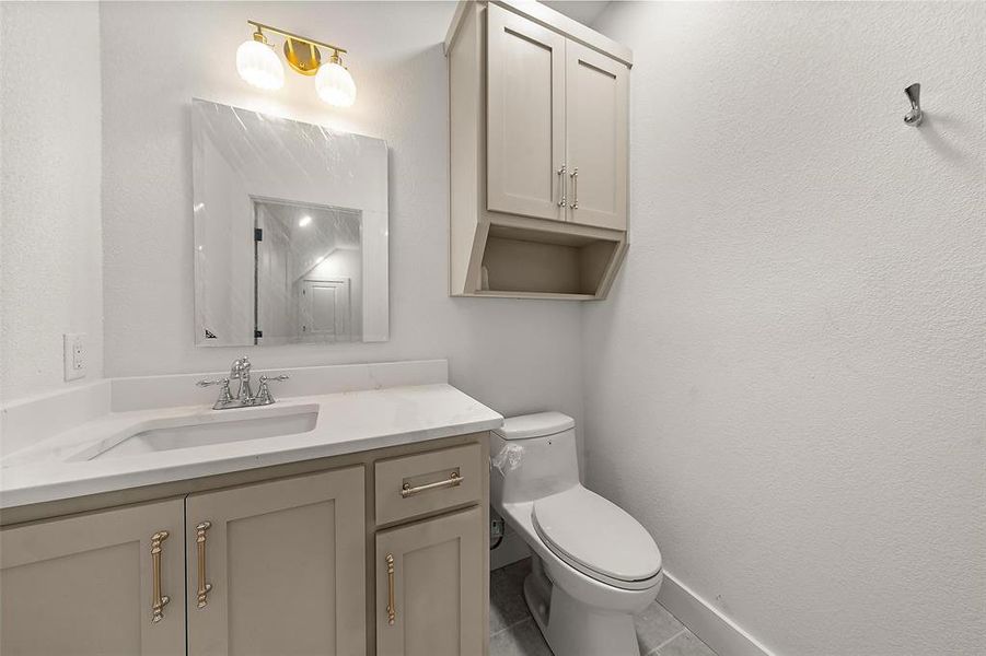 Half bath with vanity, a textured wall, and tile patterned flooring Half bath with vanity, a textured wall, and tile patterned flooring