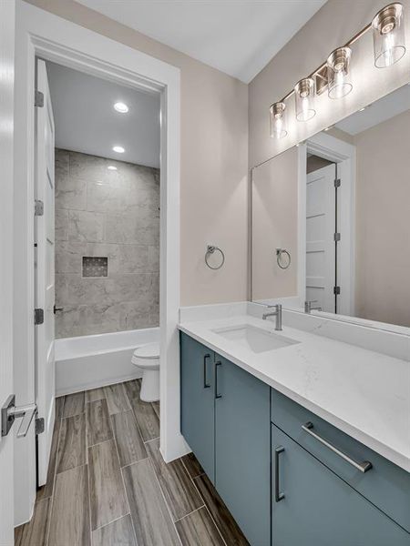 Full bathroom with tiled shower / bath, vanity, and toilet