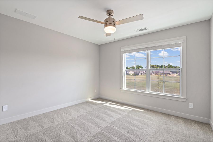 Expansive window, neutral wall palette, textured carpeting, and a ceiling fan with integrated lighting