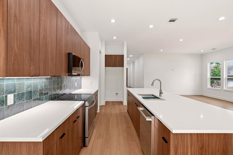 Kitchen with modern cabinets, stainless steel appliances, light wood finished floors, a large island, and wood finish cabinets