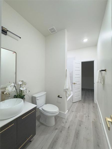 Full bathroom with toilet, vanity, hardwood / wood-style flooring, and shower / bathtub combination