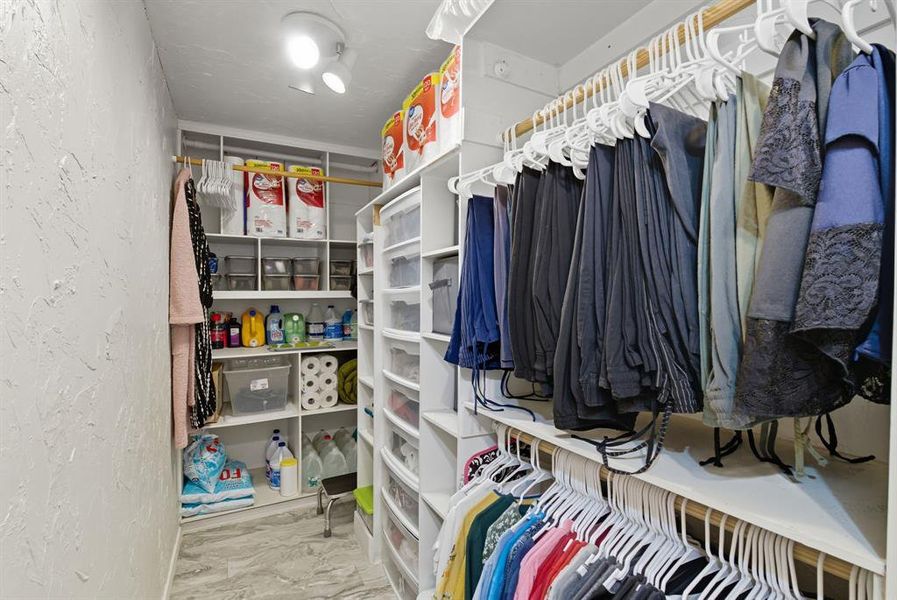 Walk in closet featuring light marble finish flooring Walk in closet featuring light marble finish flooring