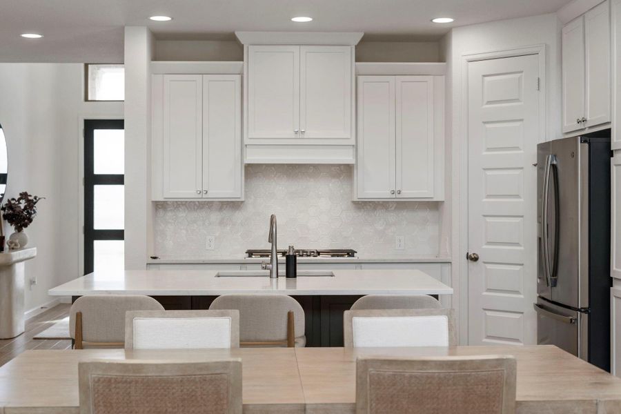 Symmetrical view of the kitchen workspace highlighting the designer hexagonal tile backsplash and pristine white cabinetry. Symmetrical view of the kitchen workspace highlighting the designer hexagonal tile backsplash and pristine white cabinetry.