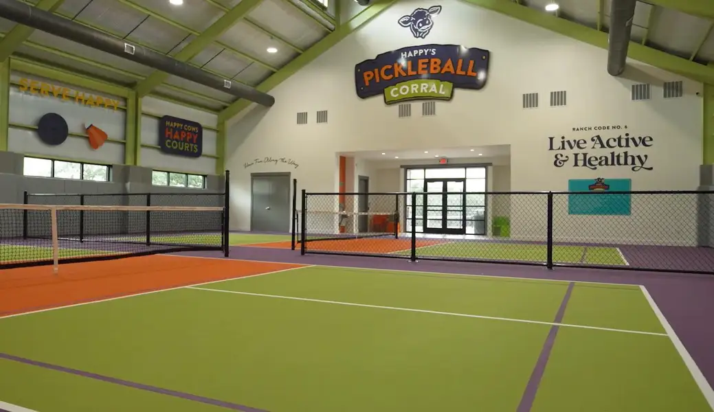 An indoor pickleball court, where vibrant playing surfaces and ample lighting create an energetic recreational space.