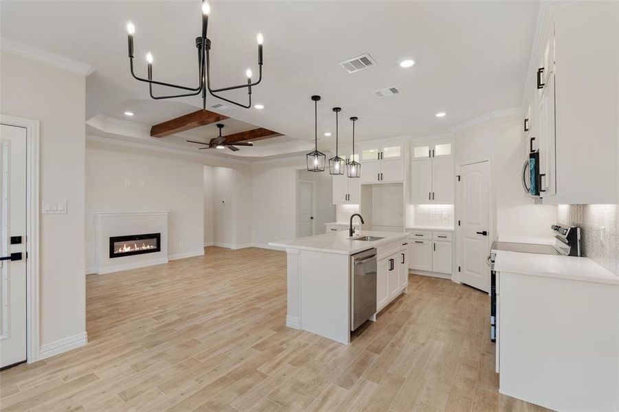 Kitchen featuring a kitchen island with sink, ceiling fan with notable chandelier, white cabinetry, light hardwood / wood-style flooring, and stainless steel appliances